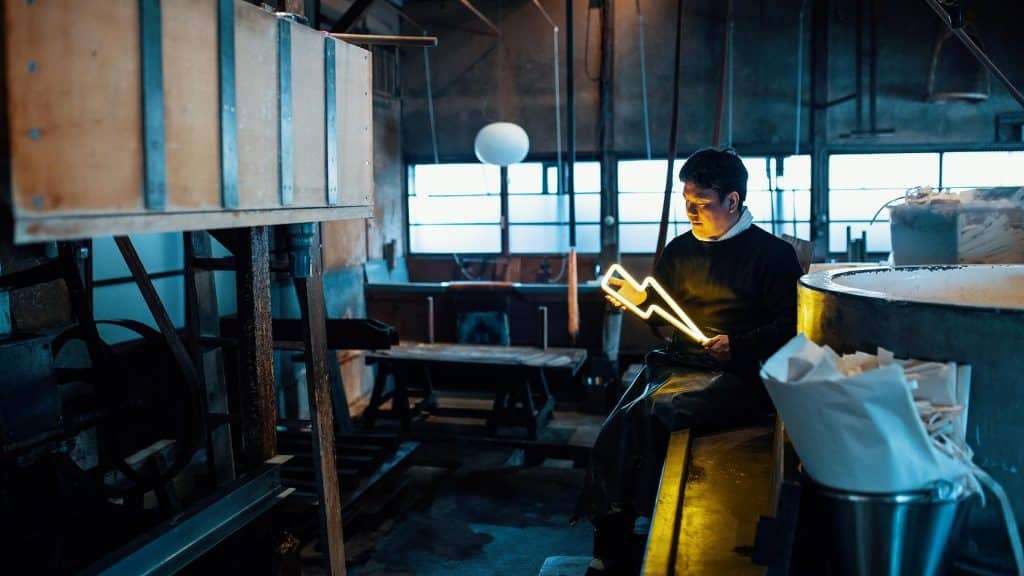 Handmade paper artist holding neon light in lightning shape